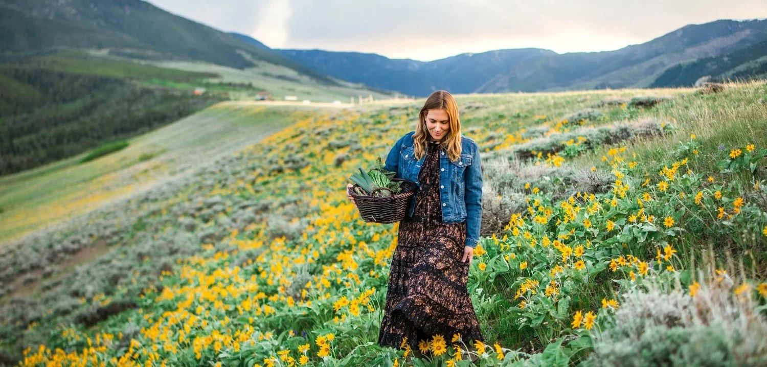 Dr. Michele Burklund standing in a field of wildflowers beneath the mountains