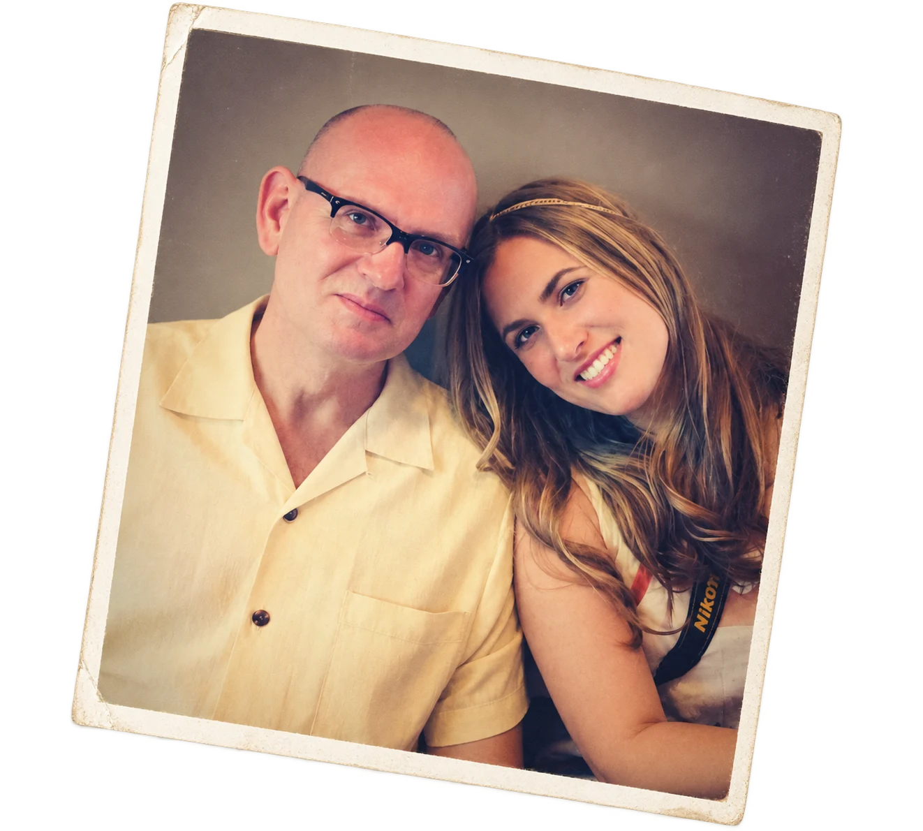 A man and young woman taking a selfie together, smiling, with the woman leaning her head on the man's shoulder.
